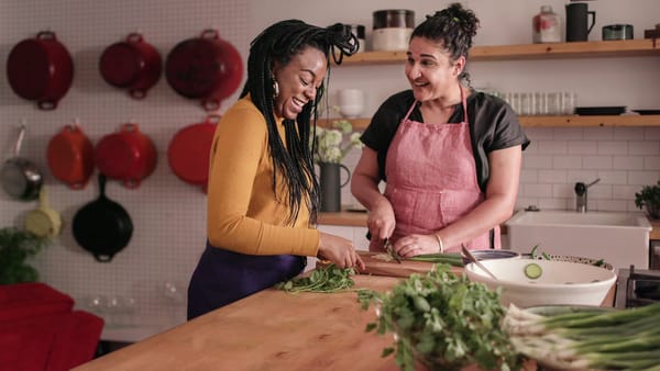 Production still from Salt, Fat, Acid Heat Netflix special: Nosrat chopping green onions with a smiling partner