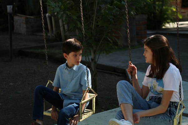 Two people talking while on swings at a playground